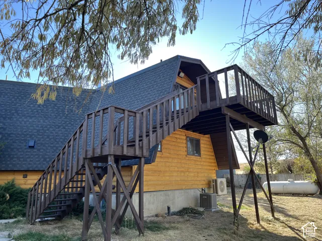 Wood-sided exterior featuring an elevated deck with wood railing, a dark shingle roof, and exterior window