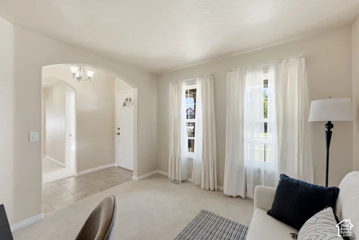 Arched entryway with a chandelier, front door with an arched window, and two double-hung windows