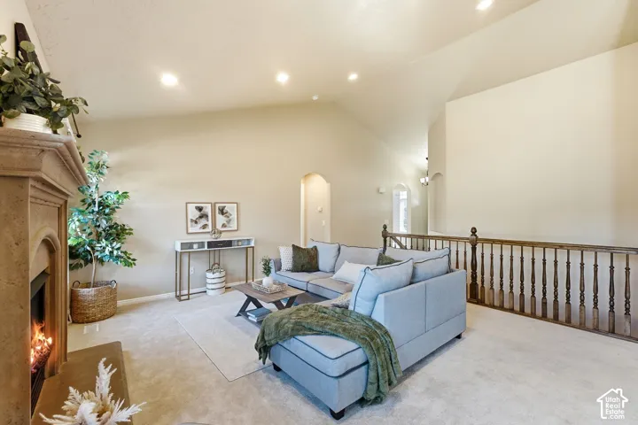 Vaulted ceilings with recessed lighting, a stone-finish fireplace, and a light-toned carpeted floor