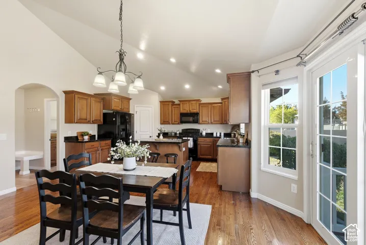 Vaulted ceilings with recessed lighting, wood-finish flooring, kitchen with dark cabinetry and countertops, and French doors
