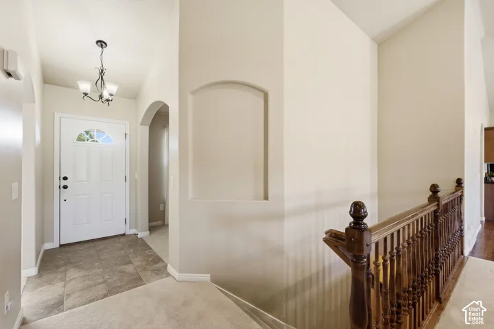 Entryway featuring a decorative arched niche, chandelier lighting, and a white paneled door with an arched transom window