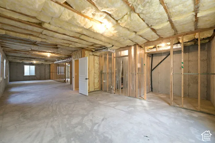 Expansive unfinished basement featuring concrete flooring, exposed wood framing, and ceiling insulation