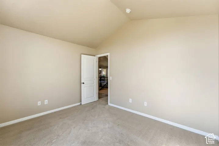 Vaulted ceiling with neutral wall tones and carpeted flooring