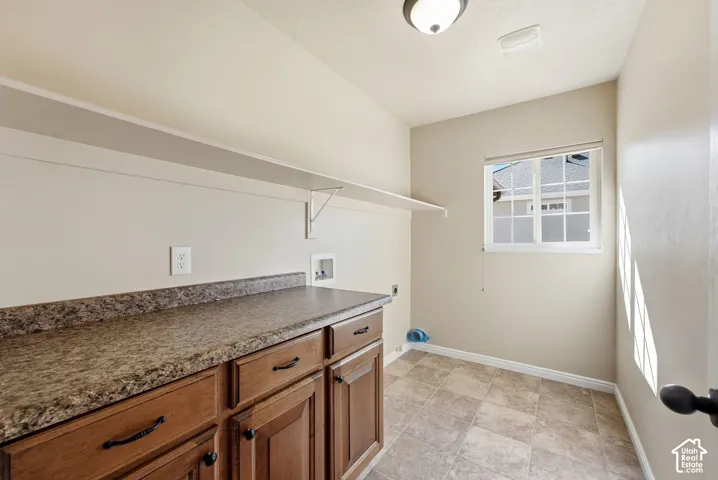 Wood-finish cabinetry with dark hardware, a spacious countertop, overhead shelving, and a dual-pane window