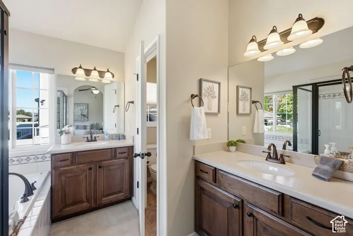 Double vanity with warm wood-finish cabinetry, integrated sinks, and polished bronze fixtures