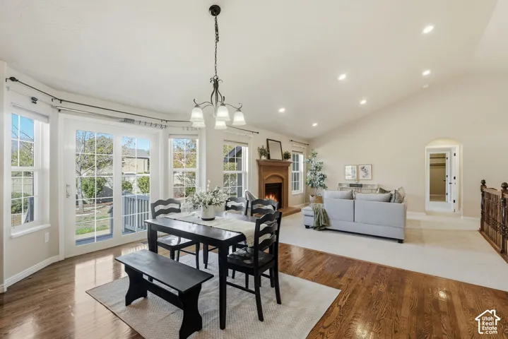 Vaulted ceiling, recessed lighting, wood-finish flooring, fireplace with wood mantel, and a multi-pane glass door