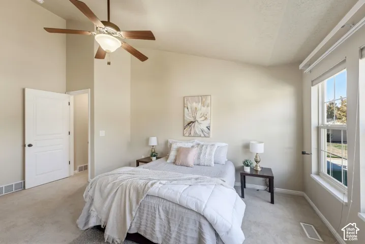 Vaulted ceiling, ceiling fan with integrated lighting, carpeted flooring, white trim, and a double-pane window