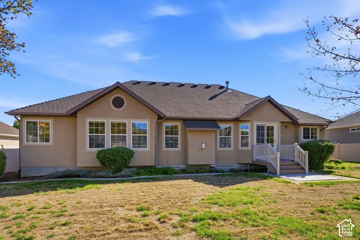 Stucco exterior with multiple windows, a rear deck, and a ground-level patio