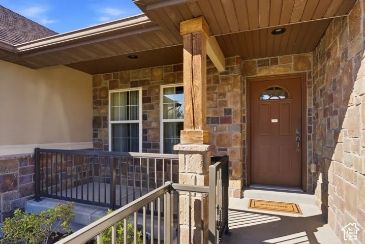 Stone facade with a covered entry, wood-finish porch ceiling, and a solid wood entry door with an arched window