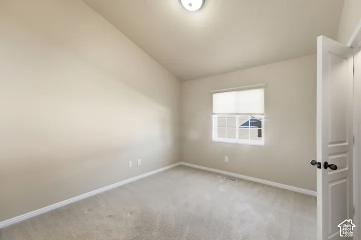 Angled ceiling, neutral wall paint, carpeted flooring, window with blinds, panel interior door