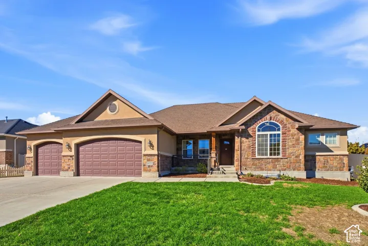 Stone and stucco exterior with an arched window, a two-car garage, and a covered entry