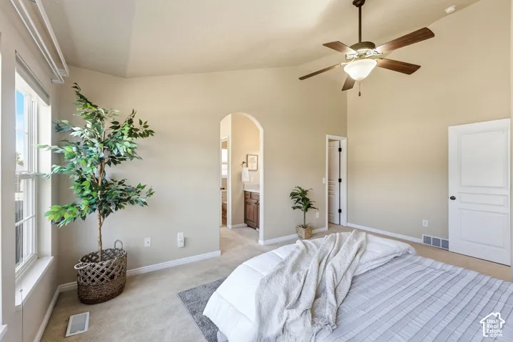 Vaulted ceiling, ceiling fan, carpeted flooring, window with blinds, arched doorway
