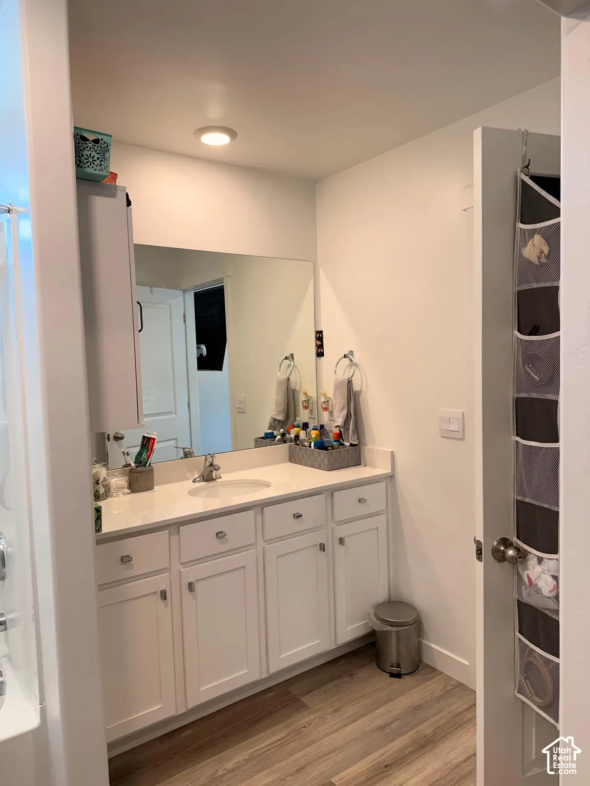 White shaker-style vanity with a light-toned countertop, integrated sink, and a large wall-mounted mirror