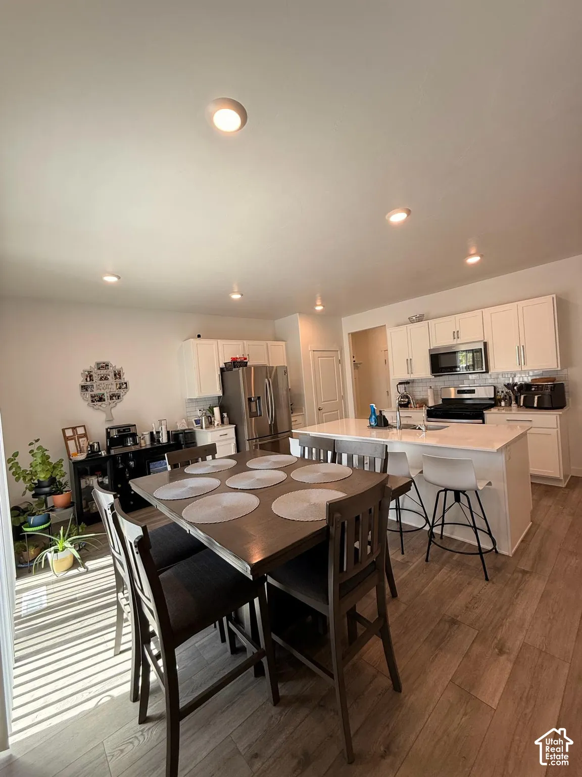 Open-concept kitchen and dining area featuring recessed lighting, wood-finish flooring, and white cabinetry