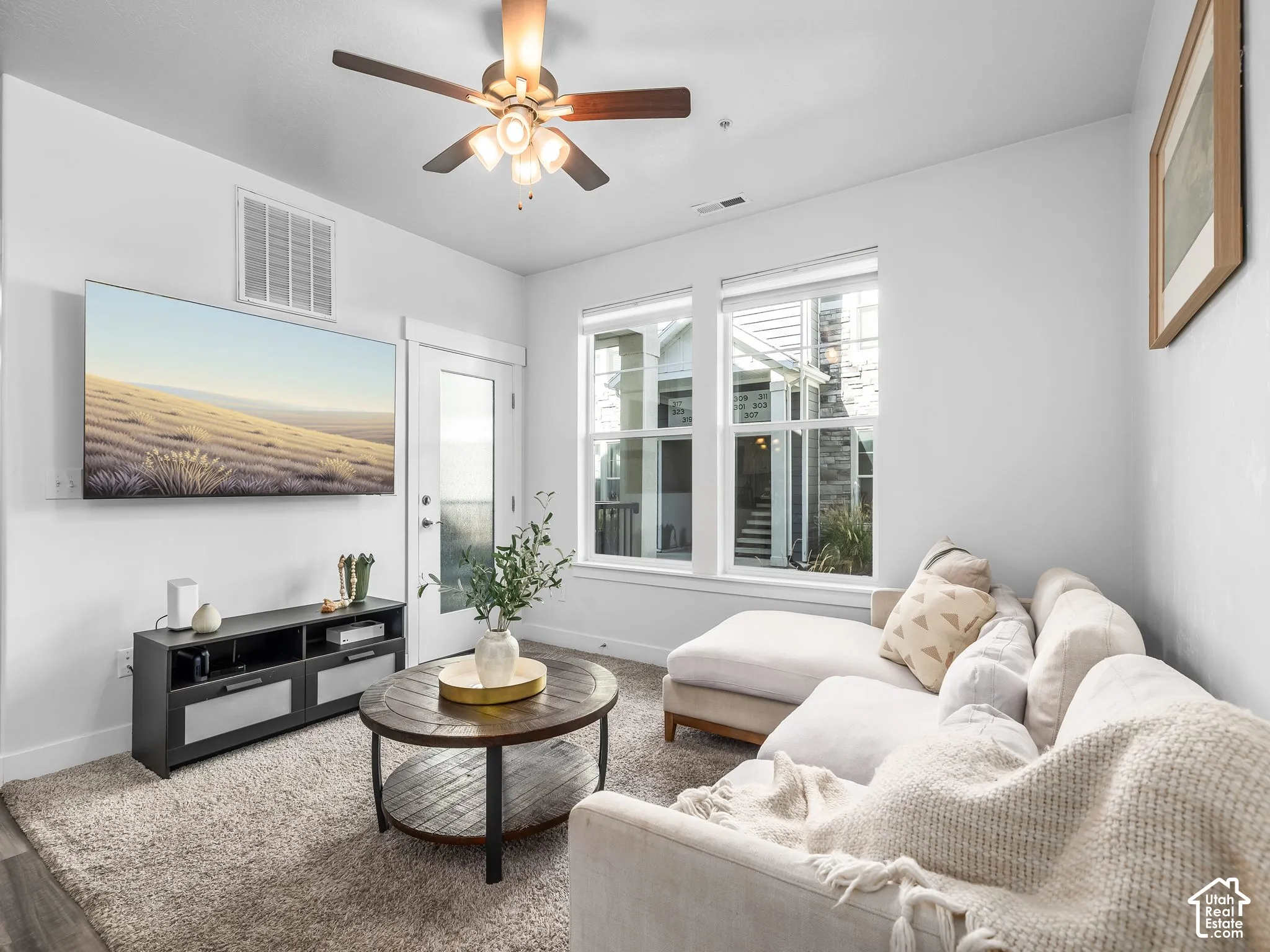 Wood-finish flooring, ceiling fan, white trim, and a glass-paneled door