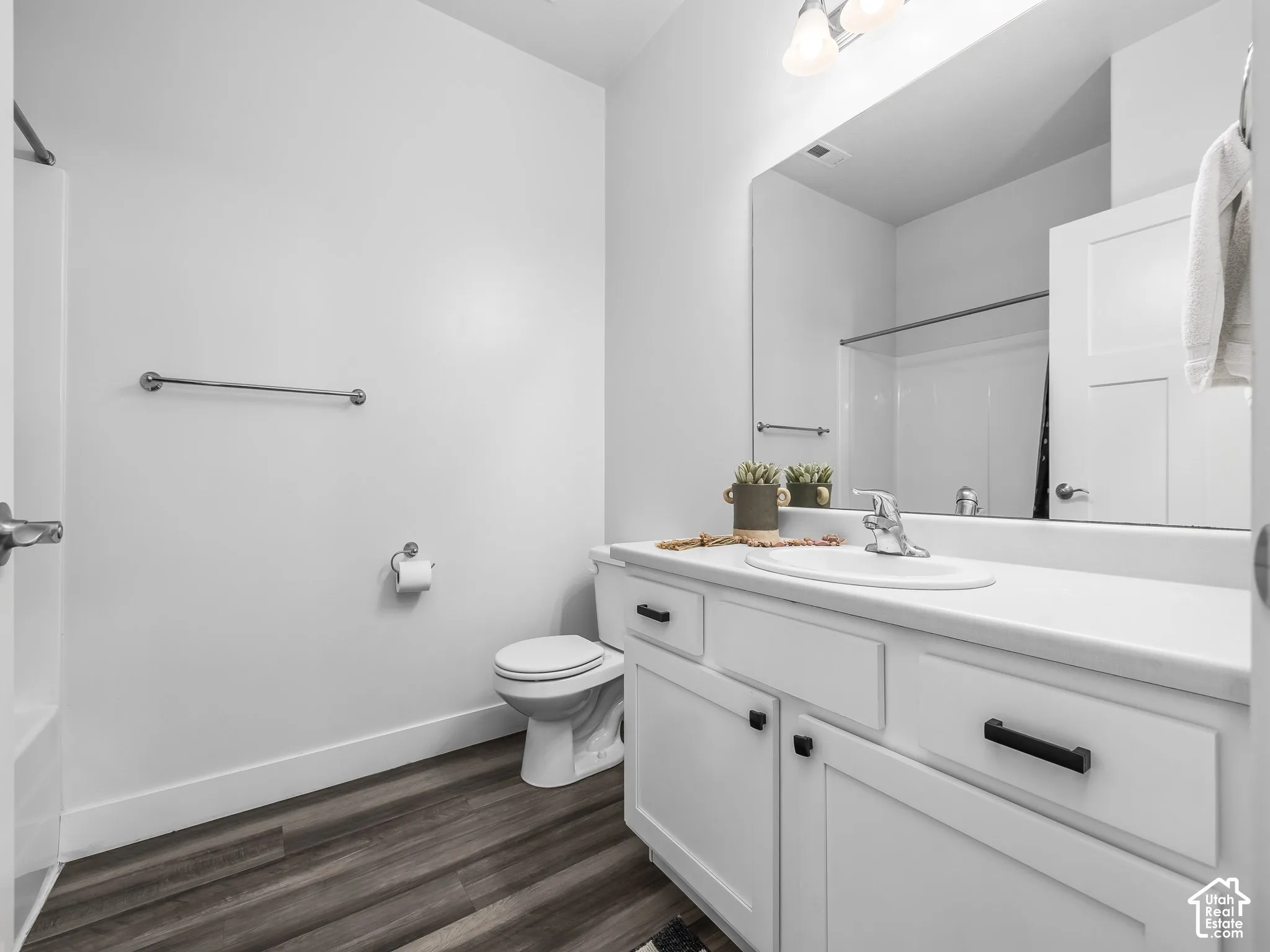 Bathroom featuring a single vanity with white cabinetry, a built-in sink, and a rectangular wall-mounted mirror