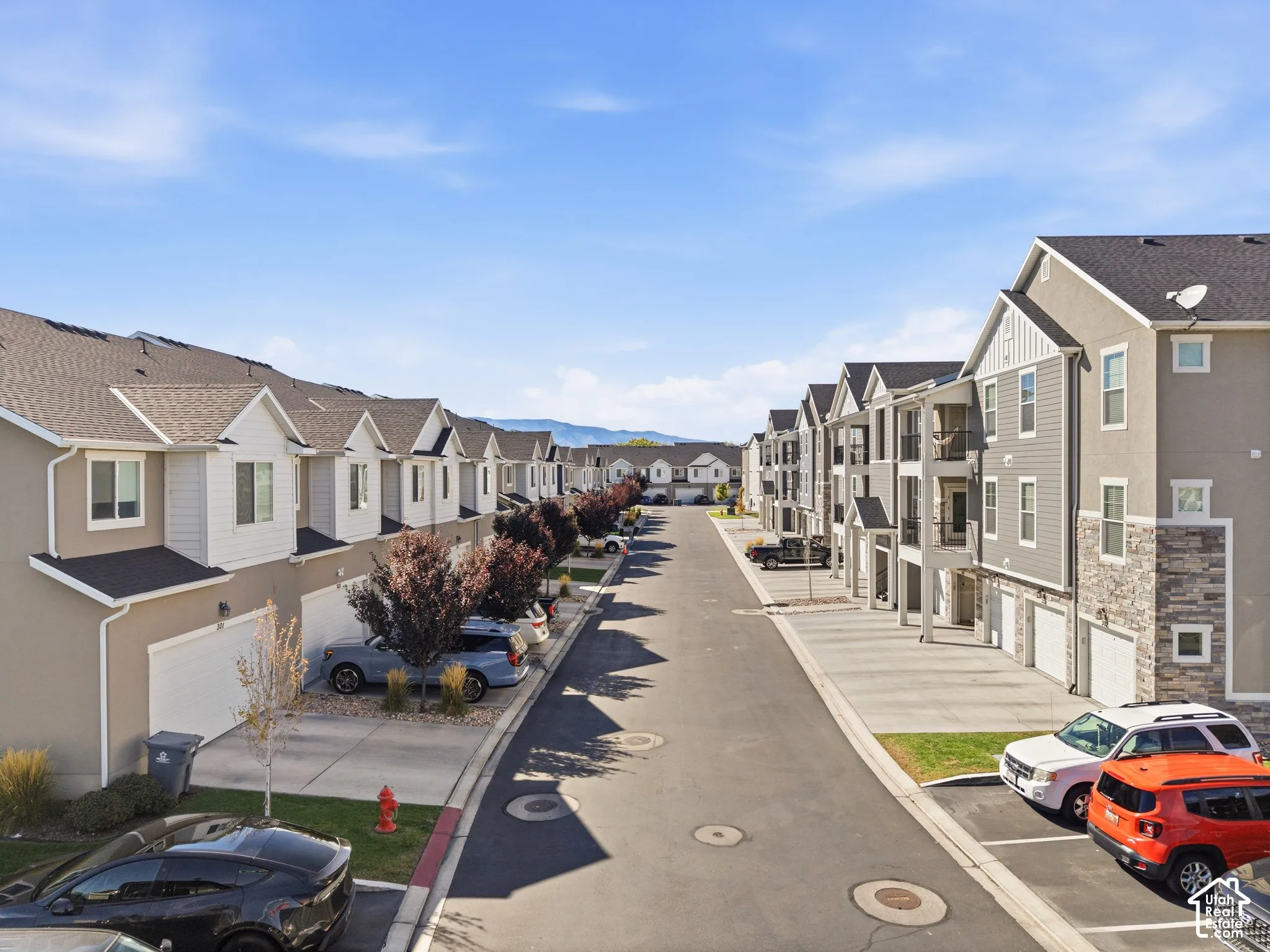 Row of multi-story residential buildings featuring gabled roofs and individual garages