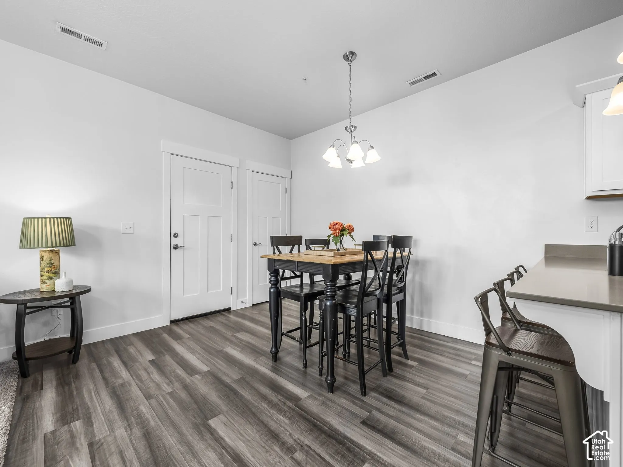 Wood-finish flooring, white walls, and a multi-light chandelier