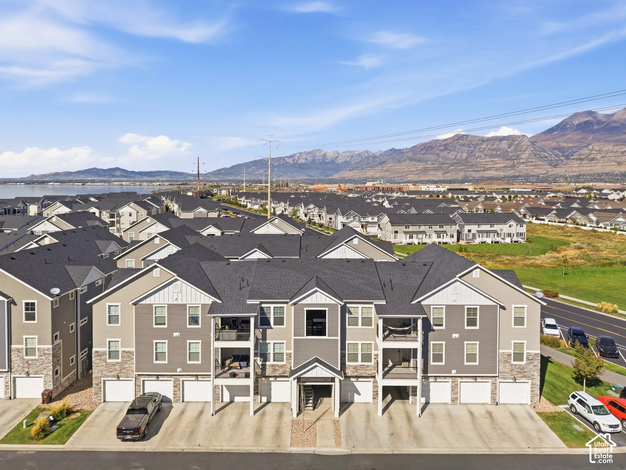 Multi-story residential complex featuring private balconies, attached garages, and stone-clad lower levels