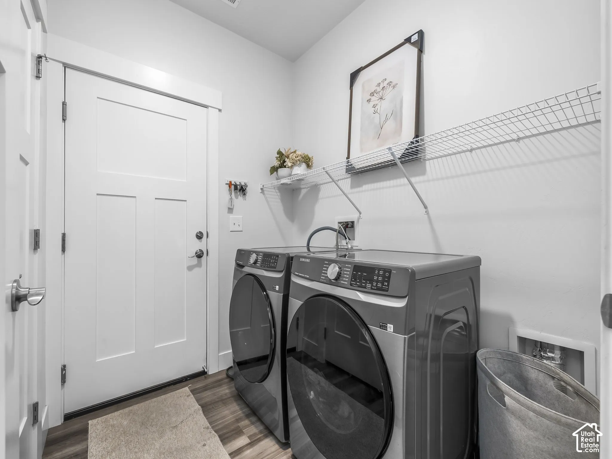 Dedicated laundry area featuring wood-finish flooring, white paneled doors, and wall-mounted wire shelving