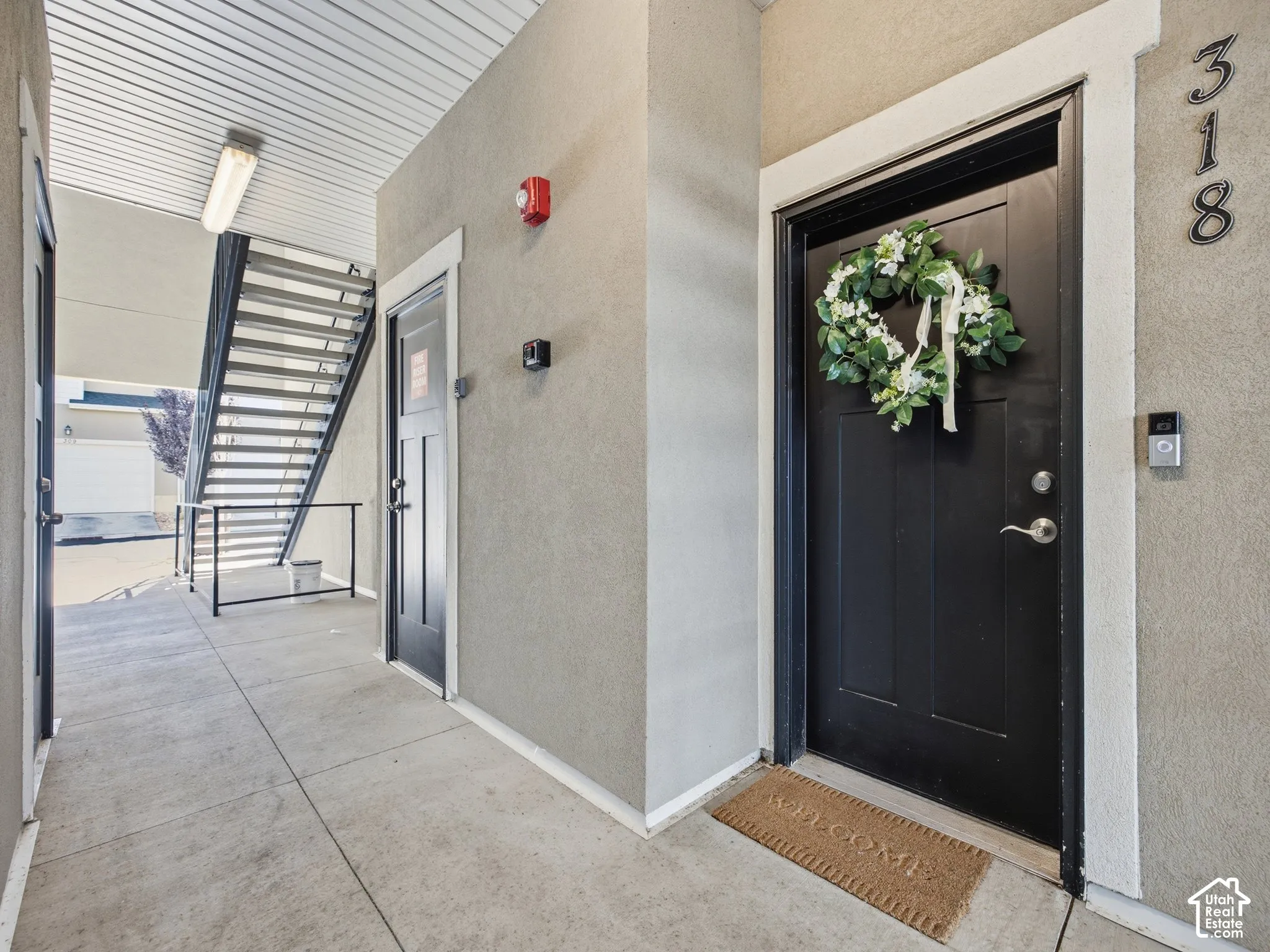 Corridor entry featuring concrete flooring, textured walls, and a black paneled door with white trim
