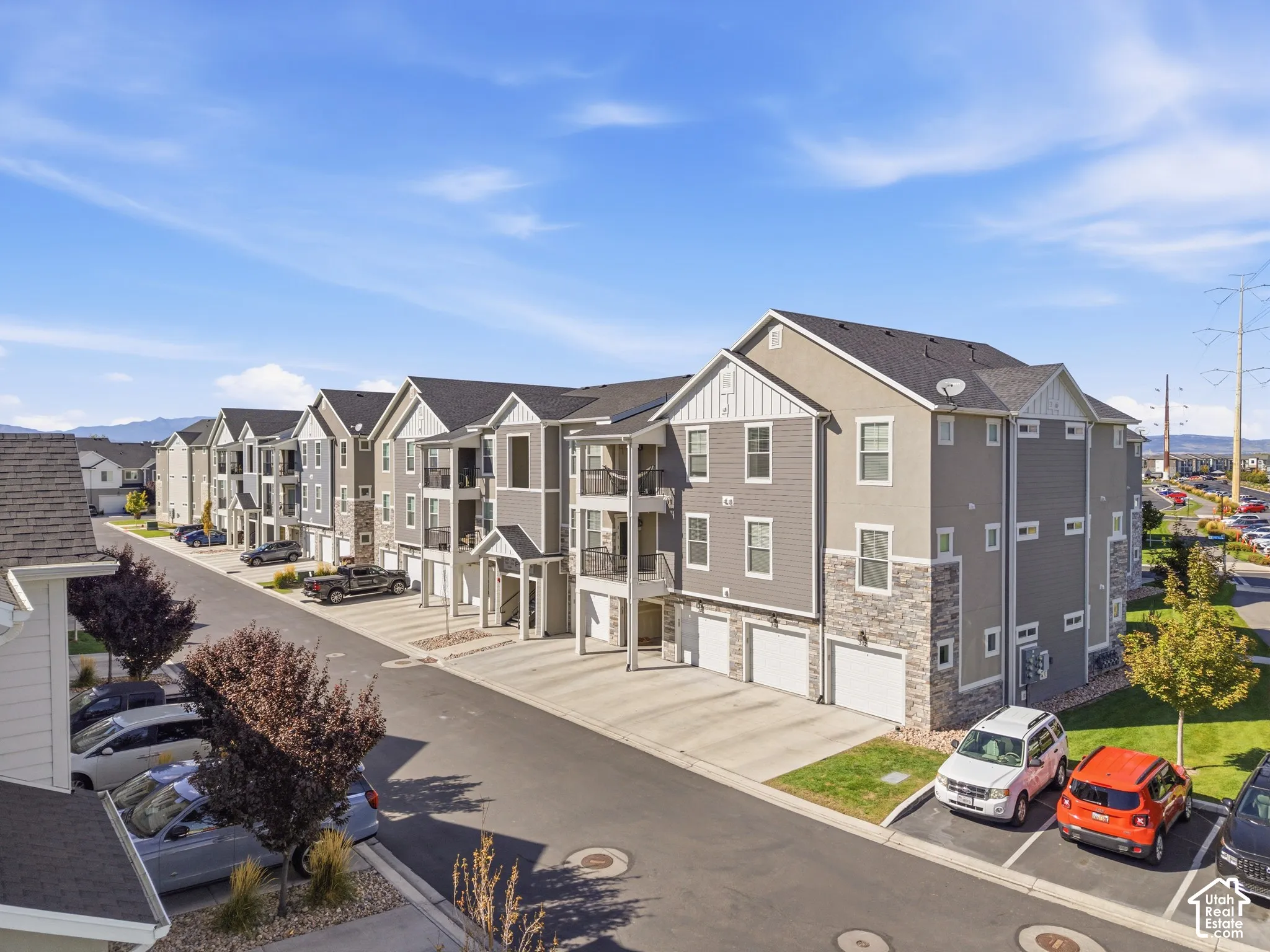 Multi-story residential buildings featuring gabled roofs, stone veneer accents, and individual garage access