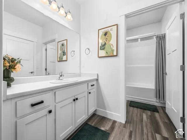 Spacious bathroom featuring a single vanity with extensive countertop space, white cabinetry, and wood-finish flooring
