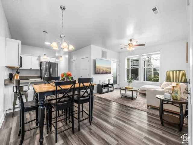 Open-concept living space with wood-finish flooring, white cabinetry, and stainless steel appliances