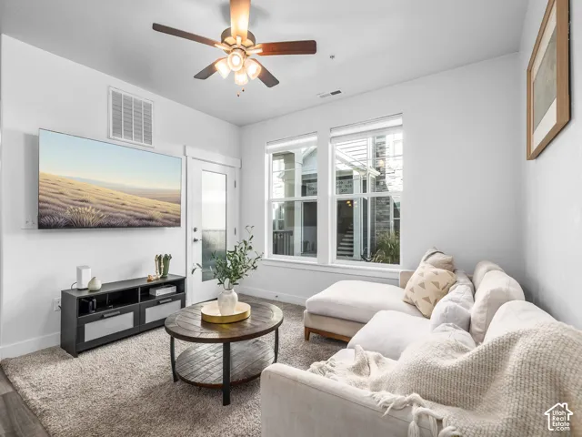Wood-finish flooring, ceiling fan, white trim, and a glass-paneled door