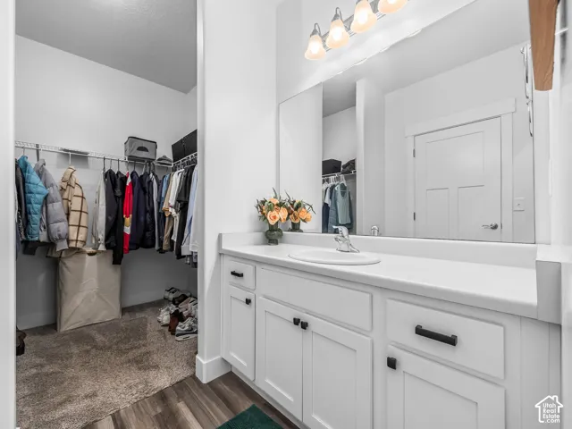 White vanity with a built-in sink, dark hardware, and a large mirror
