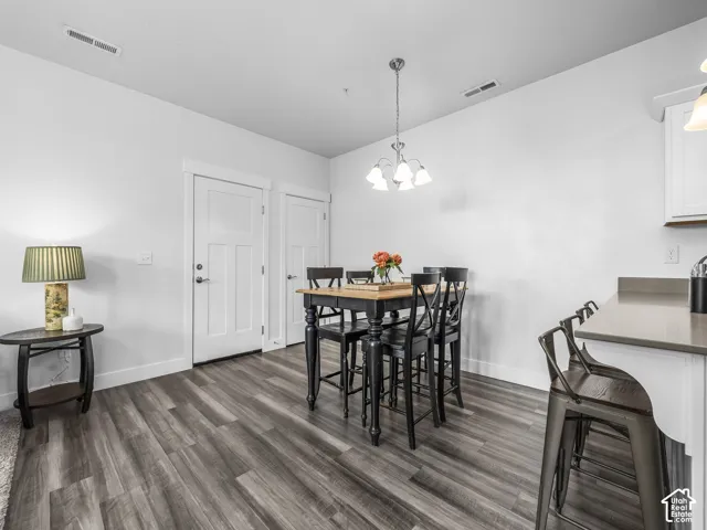 Wood-finish flooring, white walls, and a multi-light chandelier