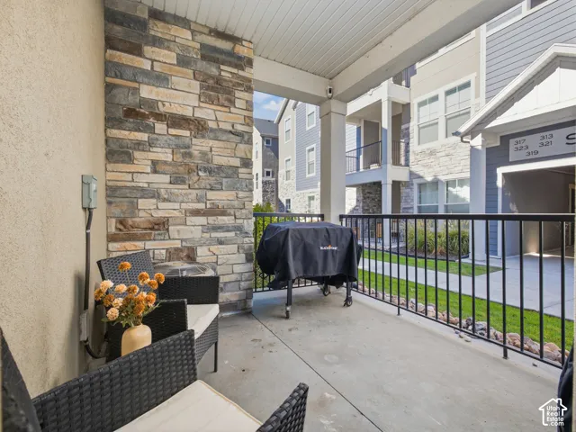 Covered patio with a concrete surface, stone veneer accent wall, and black metal railing