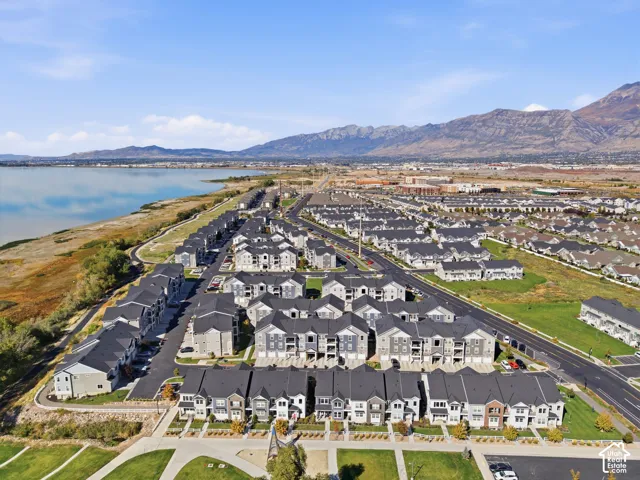 Aerial perspective showcasing a residential community with varied architectural styles, a prominent body of water, and distant mountain ranges