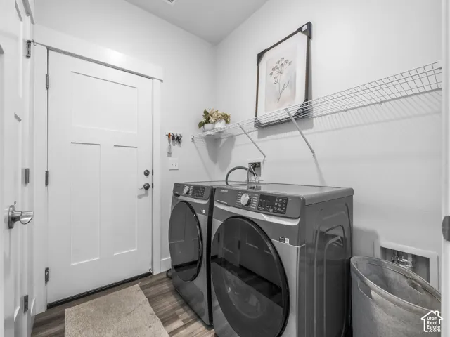 Dedicated laundry area featuring wood-finish flooring, white paneled doors, and wall-mounted wire shelving