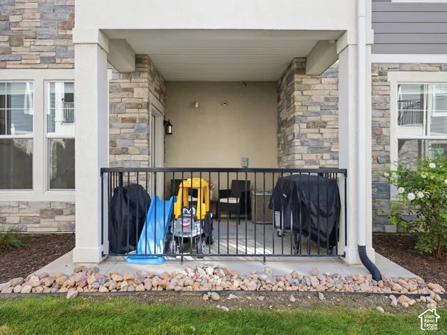 Covered patio with a concrete floor, black metal railing, and stone veneer accents