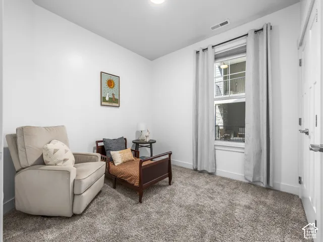 White painted walls with wall-to-wall carpeting and a single window offering natural light
