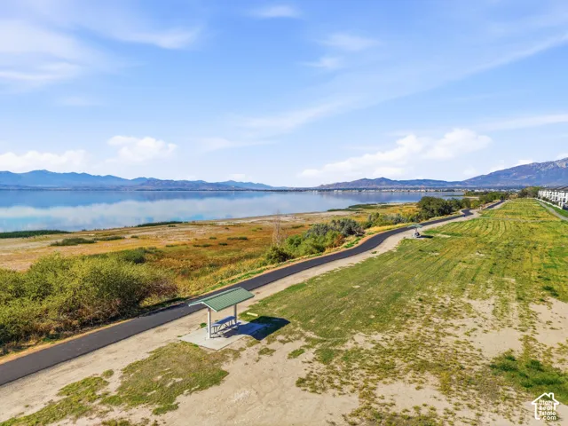 Waterfront property with a paved pathway, expansive grassy area, and a picnic shelter