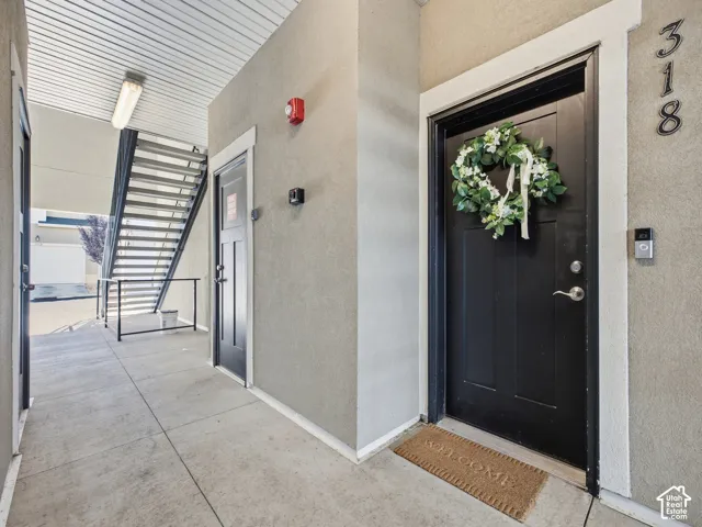 Corridor entry featuring concrete flooring, textured walls, and a black paneled door with white trim