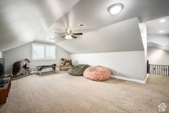 Spacious upper-level room featuring vaulted ceilings with ceiling fan, recessed lighting, and abundant natural light from multiple windows with plantation shutters