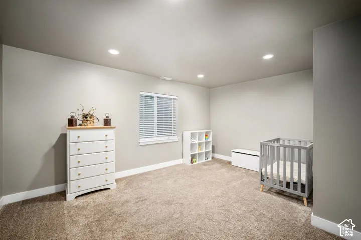 Bright nursery featuring recessed ceiling lighting, carpet flooring, and ample natural light from a shuttered window
