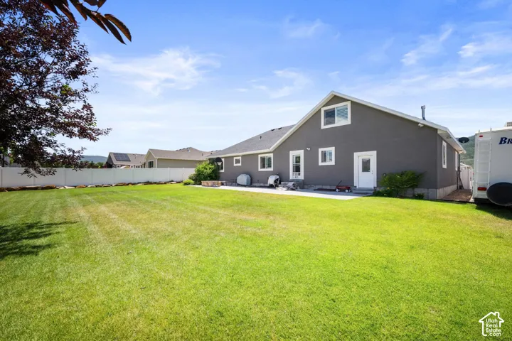 Expansive green lawn, white perimeter fencing, and concrete patio area