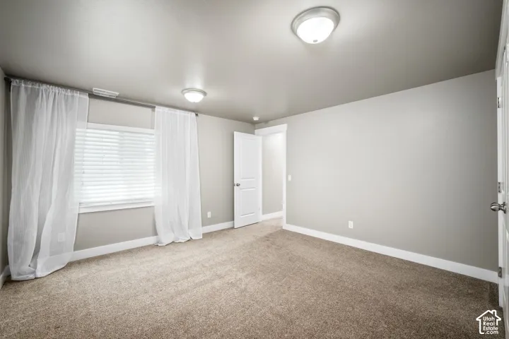 Spacious bedroom with neutral wall finishes, recessed ceiling lighting, and plush carpeting throughout