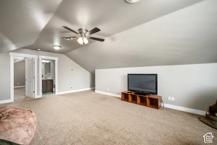 Spacious bonus room with vaulted ceilings, ceiling fan with integrated lighting, and neutral carpeting