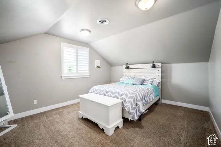 Bright second-floor bedroom with vaulted ceilings, recessed lighting, and a casement window providing natural light