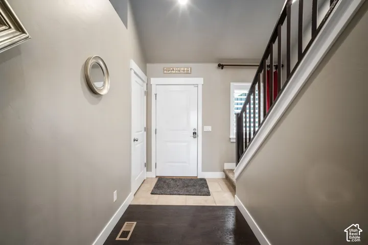 Foyer featuring a two-tone flooring design, white paneled doors, and a staircase with dark balusters