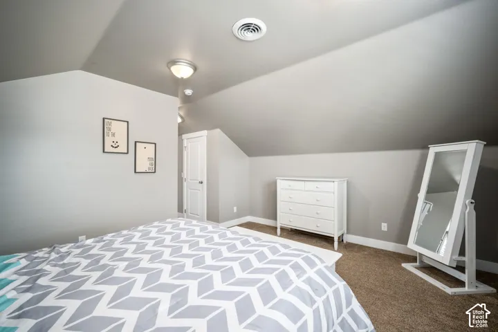 Bright attic bedroom featuring sloped ceilings, recessed lighting, and neutral wall finishes