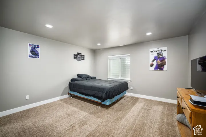 Spacious bedroom with recessed ceiling lighting, neutral wall finishes, and carpeted flooring