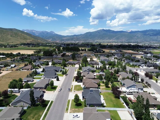 Residential neighborhood featuring a paved street, established homes, green spaces, and mountain backdrop