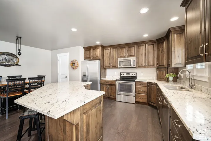 Kitchen featuring extensive cabinetry with modern hardware, stone countertops, and stainless steel appliances