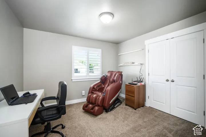 White paneled closet doors, window with white plantation shutters, neutral-toned walls, and carpet flooring